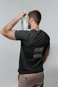 Man wearing a black t-shirt with 'Here for the Beer' text, holding a bottle against a plain background
